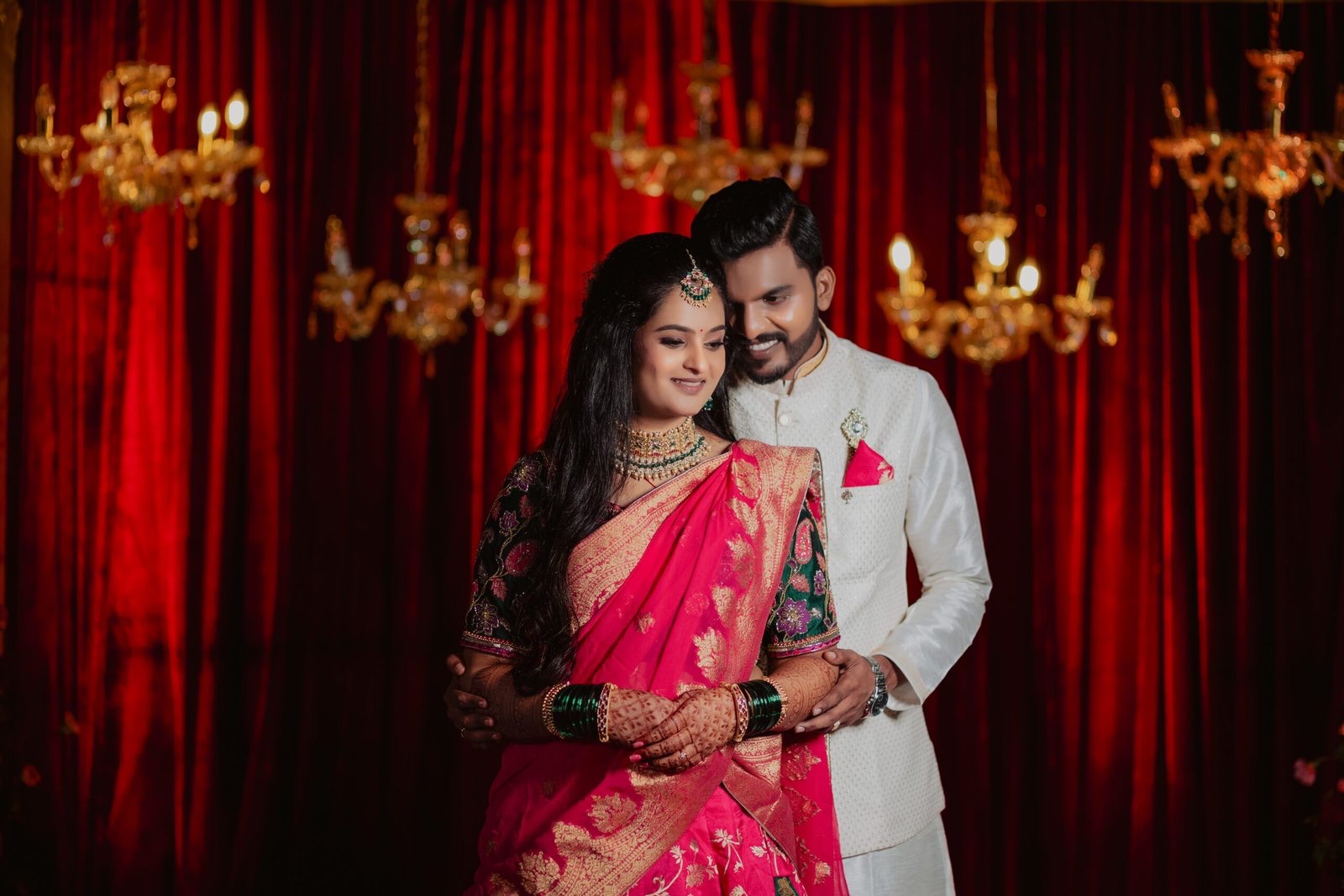 Couple against red curtains and chandeliers